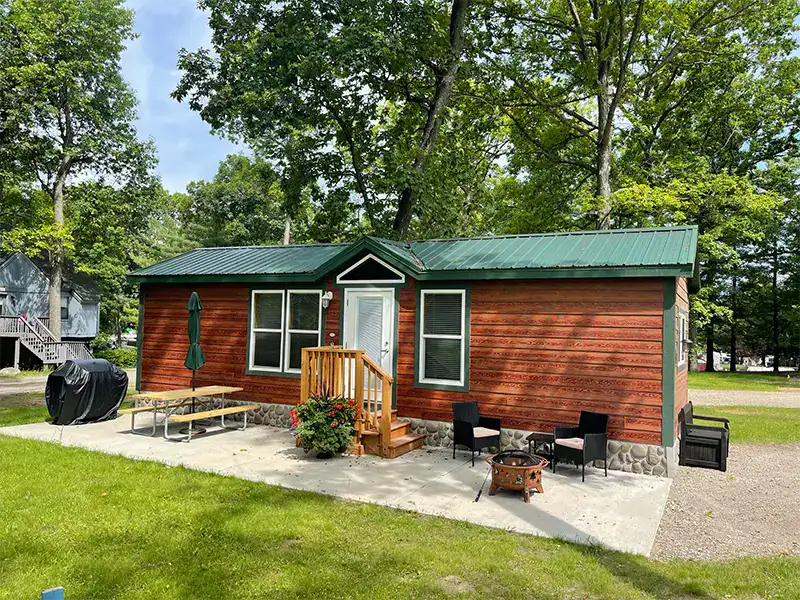 Charming cabin with outdoor seating near trees at Waldenwoods Recreation Resort.
